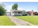 View of home with a driveway leading to a detached garage and a lush green lawn at 1020 N Ritter Ave, Indianapolis, IN 46219