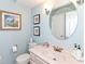 Powder room with framed art and round mirror over the vanity with framed mirror and matching faucet at 11030 Brentwood Ave, Zionsville, IN 46077