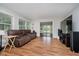 Comfortable living room featuring wood floors, large windows, and a dark brown leather sofa and media center at 16714 Oak Rd, Westfield, IN 46074