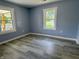 An empty, freshly painted blue bedroom features luxury vinyl plank flooring and two windows at 1818 Broadway St, Anderson, IN 46012