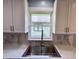 Close-up of kitchen sink and window featuring granite countertops and white shaker cabinets at 1818 Broadway St, Anderson, IN 46012