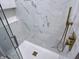 A gorgeous walk-in shower is tiled in a stunning marble pattern with gold hardware at 1818 Broadway St, Anderson, IN 46012