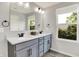 Bathroom featuring a double vanity with gray cabinets, modern fixtures, and ample natural light from a nearby window at 2074 Tompkins Dr, Westfield, IN 46074
