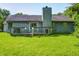 View of the back of house with a deck and large yard featuring a brick chimney and grey siding at 3816 Cologne Ct, Indianapolis, IN 46228