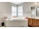 Bright bathroom featuring a large tiled soaking tub and wooden vanity with sink at 3816 Cologne Ct, Indianapolis, IN 46228