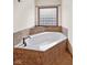 Bathroom with a corner bathtub with stone-look surround and a privacy glass block window at 5274 Brooks Bnd, Greenwood, IN 46143