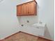 Practical laundry room boasts a utility sink, upper cabinets, and tile flooring at 5274 Brooks Bnd, Greenwood, IN 46143