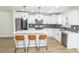 Bright kitchen with white cabinetry, stainless steel appliances, a center island with bar stools, and a stylish herringbone backsplash at 5707 In-234, McCordsville, IN 46055