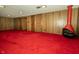 Basement featuring wood paneled walls, red carpet and a striking red fireplace at 5927 Meadowood Dr, Speedway, IN 46224