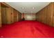 Basement area with classic wood paneling, red carpet and a retro-style fireplace at 5927 Meadowood Dr, Speedway, IN 46224