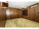 Finished basement with a carpeted floor, wood paneled walls and built in storage shelves at 5927 Meadowood Dr, Speedway, IN 46224