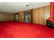 Spacious basement area with retro wood paneling, red carpeting, and a red fireplace at 5927 Meadowood Dr, Speedway, IN 46224