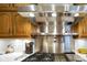 A stainless steel range hood is featured over a cooktop with white tile backsplash and wood cabinets at 6118 Deerwood Dr, Greenwood, IN 46143