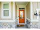 Inviting front entryway with a vibrant orange door and stone accents at 7284 Bayview Run, McCordsville, IN 46055