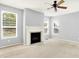 Bright living room with neutral carpet, ceiling fan, large windows and a classic fireplace with white mantle at 7337 Wythe Dr, Noblesville, IN 46062