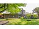 Backyard view highlighting the brick exterior, chimney, deck, and lush lawn with garden beds at 8117 Scarborough Ct, Indianapolis, IN 46256