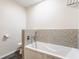 Bathroom with a large white bathtub with silver fixtures and decorative gray tile at 8117 Scarborough Ct, Indianapolis, IN 46256