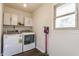 Bright laundry room with modern washer and dryer, overhead cabinets, and a window for natural light at 8117 Scarborough Ct, Indianapolis, IN 46256