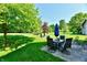 Spacious backyard with a stone patio, green grass, mature trees, and outdoor seating at 8460 Brittany N Ct, Indianapolis, IN 46236