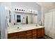 Bathroom with dual sinks, wooden vanity, and a large mirror with vanity lighting at 8460 Brittany N Ct, Indianapolis, IN 46236