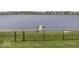 A fenced backyard with grassy lawn, lake view and waterfront access with dock featuring two American flags at 8864 S Tibbs Ave, Indianapolis, IN 46217