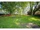 A spacious backyard with a large grassy area, landscaping, mature trees, and play accessories at 9420 N Kenwood Ave, Indianapolis, IN 46260