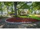 A beautifully landscaped backyard with mature trees, brick edging, mulch beds, and a grassy area at 9420 N Kenwood Ave, Indianapolis, IN 46260