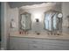Bathroom featuring double sinks, marble counters, decorative mirrors, and modern lighting at 9420 N Kenwood Ave, Indianapolis, IN 46260