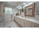 Bathroom featuring double sinks, natural light, marble counters, and decorative copper framed mirrors at 9420 N Kenwood Ave, Indianapolis, IN 46260