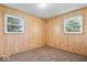Bedroom with tan carpet, wood paneled walls, and two windows at 10928 W Jackson St, Muncie, IN 47304