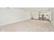 Spacious living room featuring neutral carpet, white walls, and access to the kitchen and outdoors at 11320 Lynchburg Way, Indianapolis, IN 46229