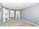 A clean bedroom with grey walls and carpet features three windows providing plenty of natural light at 117 Sawgrass Ct, Lebanon, IN 46052