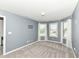 A bedroom with grey walls features three large windows providing plenty of natural light and views at 117 Sawgrass Ct, Lebanon, IN 46052