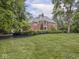 Two-story brick home with a lush green lawn surrounded by mature trees at 1207 Pickwick Pl, Indianapolis, IN 46208