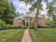 Charming two-story brick home featuring mature trees and professional landscaping along the front yard and walkway at 1207 Pickwick Pl, Indianapolis, IN 46208