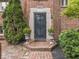 Close up shot of an ornate doorway on a brick home is flanked by manicured bushes and flowers at 1207 Pickwick Pl, Indianapolis, IN 46208