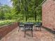 A brick patio features a table and chairs, framed by manicured bushes and a brick wall at 1207 Pickwick Pl, Indianapolis, IN 46208