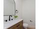 Stylish powder room features a wood vanity, modern faucet, and a round mirror at 12118 Castle Row Overlook, Carmel, IN 46033