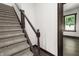 Carpeted stairs with dark wood railing and view of window in hallway at 1217 Newman St, Indianapolis, IN 46201