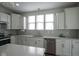 The kitchen features stainless appliances, white cabinetry, tile backsplash, and natural light from large windows at 13448 Mosaic St, Fishers, IN 46037