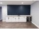 Basement bar with granite countertop, white cabinets, wine fridge, and navy wood paneling at 13820 Woodside Hollow Dr, Carmel, IN 46032