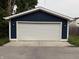 Close-up of the garage door, featuring a white door, blue siding, and modern lighting fixtures at 1720 Rembrandt St, Indianapolis, IN 46202