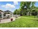 Spacious backyard with green grass, patio, outdoor dining area, fire pit, and mature trees at 19433 Tradewinds Dr, Noblesville, IN 46062