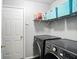 Modern laundry room with front load washer and dryer, overhead storage, and neutral gray color scheme at 19433 Tradewinds Dr, Noblesville, IN 46062