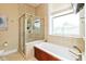 Bright bathroom features a soaking tub with wood detail and a walk-in shower with glass doors at 2105 N Meridian St # 203, Indianapolis, IN 46202