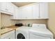 Functional laundry room featuring a sink, counter space, ample white cabinets, and a washer/dryer setup at 2105 N Meridian St # 203, Indianapolis, IN 46202