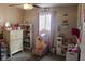 Cozy bedroom featuring a ceiling fan, a dresser, shelving unit, and a bright window at 219 N 9Th Ave, Beech Grove, IN 46107