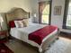 Comfortable bedroom boasts a bed with red blanket, pillows, patterned carpet and natural light from a large window at 251 North St, Danville, IN 46122