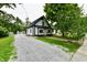Charming home featuring a gravel driveway, contrasting black and white color scheme, and mature trees at 2801 E Southport Rd, Indianapolis, IN 46227