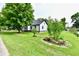 Charming home featuring mature landscaping including large trees, shrubbery, and decorative flower beds at 2801 E Southport Rd, Indianapolis, IN 46227